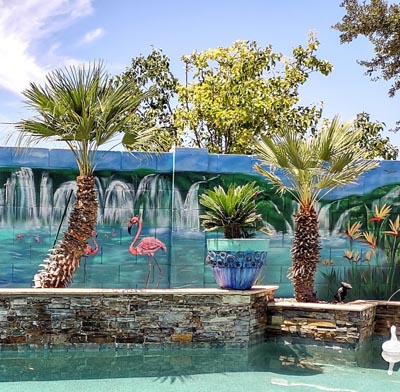 Mural tropical en el jardín con flamencos junto a la piscina.